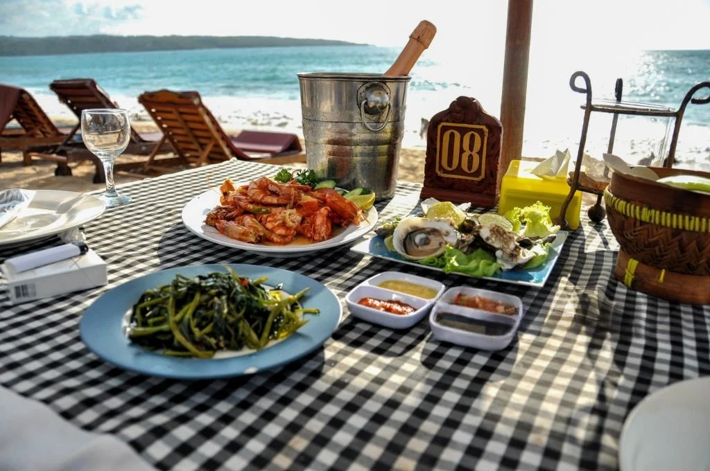 dinner jimbaran romantis dengan sunset Bali, meja pinggir pantai dan seafood